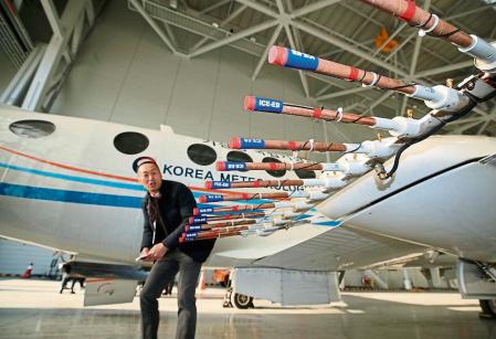This picture taken on January 24, 2019 shows a man looking at an aircraft from the Korea Meterological Administration (KMA) ready to disperse silver iodide, a compound believed to cause rain to fall, in a hanger at Gimpo airport in Seoul. - Seoul on January 25 sent aircraft over the Yellow Sea to carry out cloud-seeding experiments in an effort to tackle air pollution many South Koreans blame on China. (Photo by YONHAP / YONHAP / AFP) / - South Korea OUT / REPUBLIC OF KOREA OUT NO ARCHIVES RESTRICTED TO SUBSCRIPTION USE
